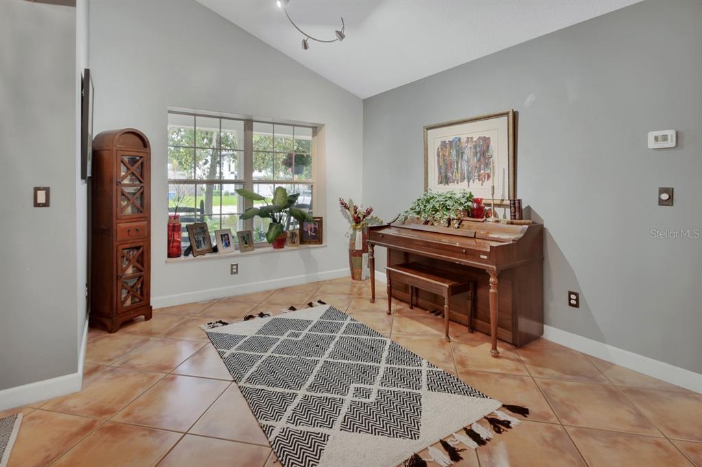 A light yellow house with a three-car garage and a brick driveway surrounded by trees — 1820 DAVIS AVENUE, DELAND, FL