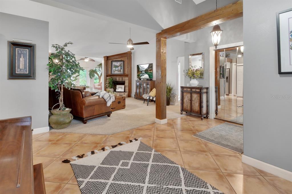 A room with tiled floors, a piano, a tall wooden cabinet, and a large window — 1820 DAVIS AVENUE, DELAND, FL