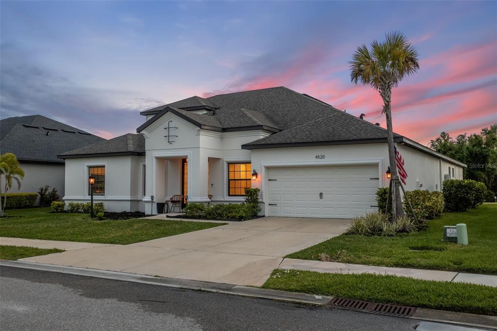A single-story suburban house with a white stucco exterior, a two-car garage, and a palm tree — 4520 POND BROOK COURT, LAKEWOOD RANCH, FL