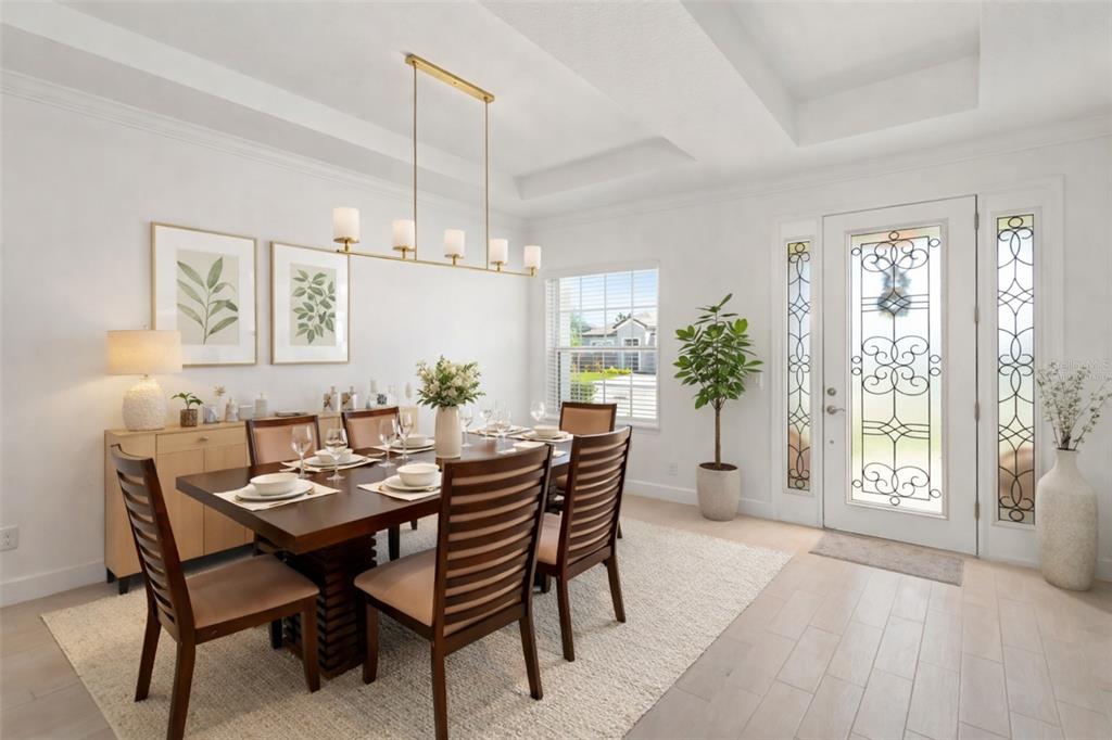 A dining room features a dark wood table, six chairs, a chandelier, and a front door — 4520 POND BROOK COURT, LAKEWOOD RANCH, FL