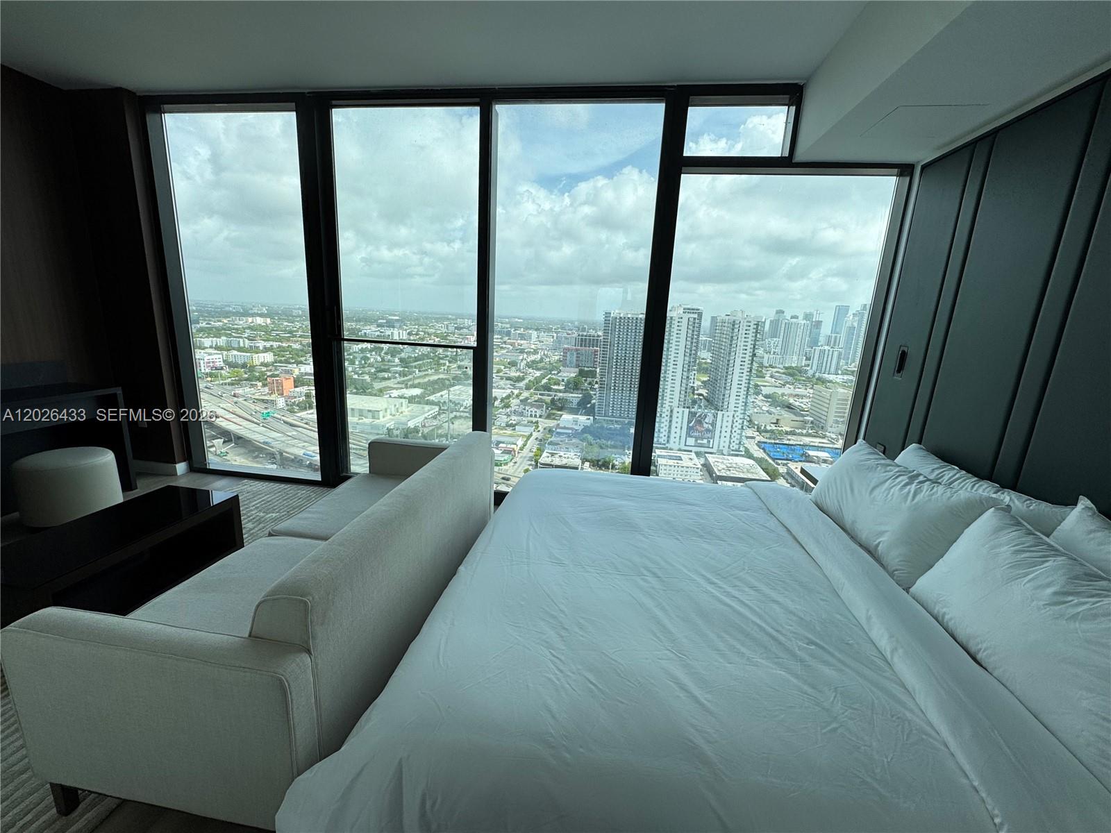 A bedroom features a bed, a sofa, and floor-to-ceiling windows overlooking a city skyline — 20 NE 11th St # 3405, Miami FL 33132, MIAMI, FL