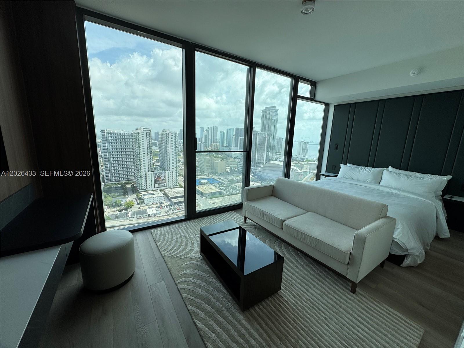 A modern bedroom features floor-to-ceiling windows with city views, a sofa, and a bed — 20 NE 11th St # 3405, Miami FL 33132, MIAMI, FL