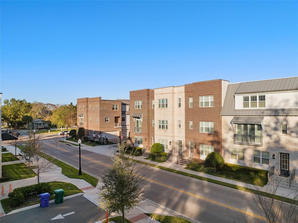 An exterior view of multi-story brick townhomes along a paved street with sidewalks — 129 S PARK AVENUE UNIT 8E, WINTER GARDEN, FL