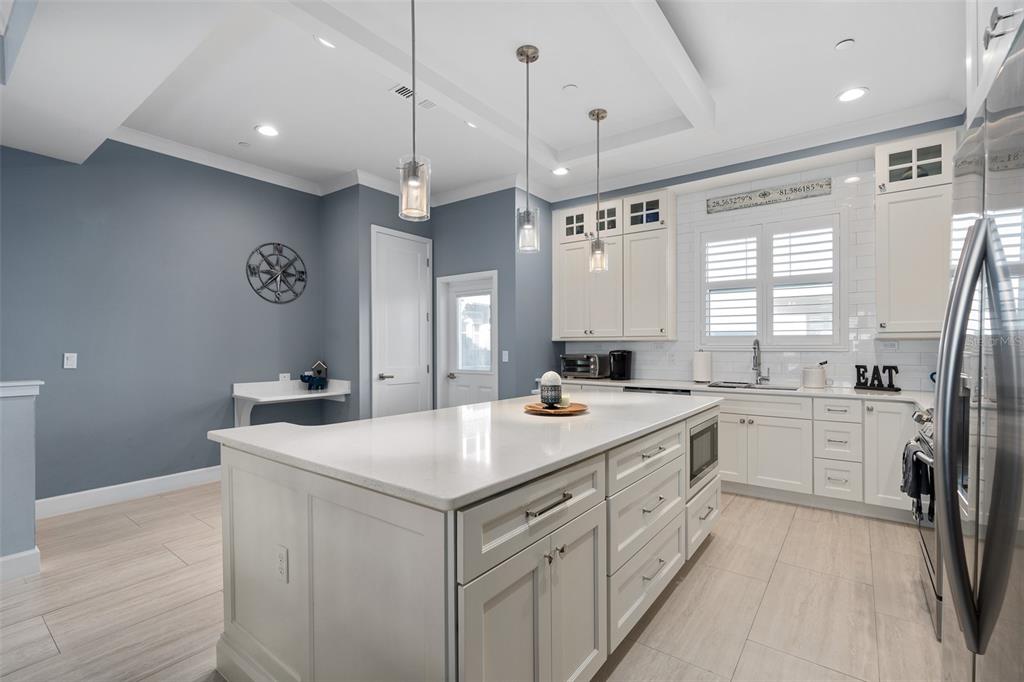 A kitchen features white cabinetry, a large central island, and blue walls — 129 S PARK AVENUE UNIT 8E, WINTER GARDEN, FL