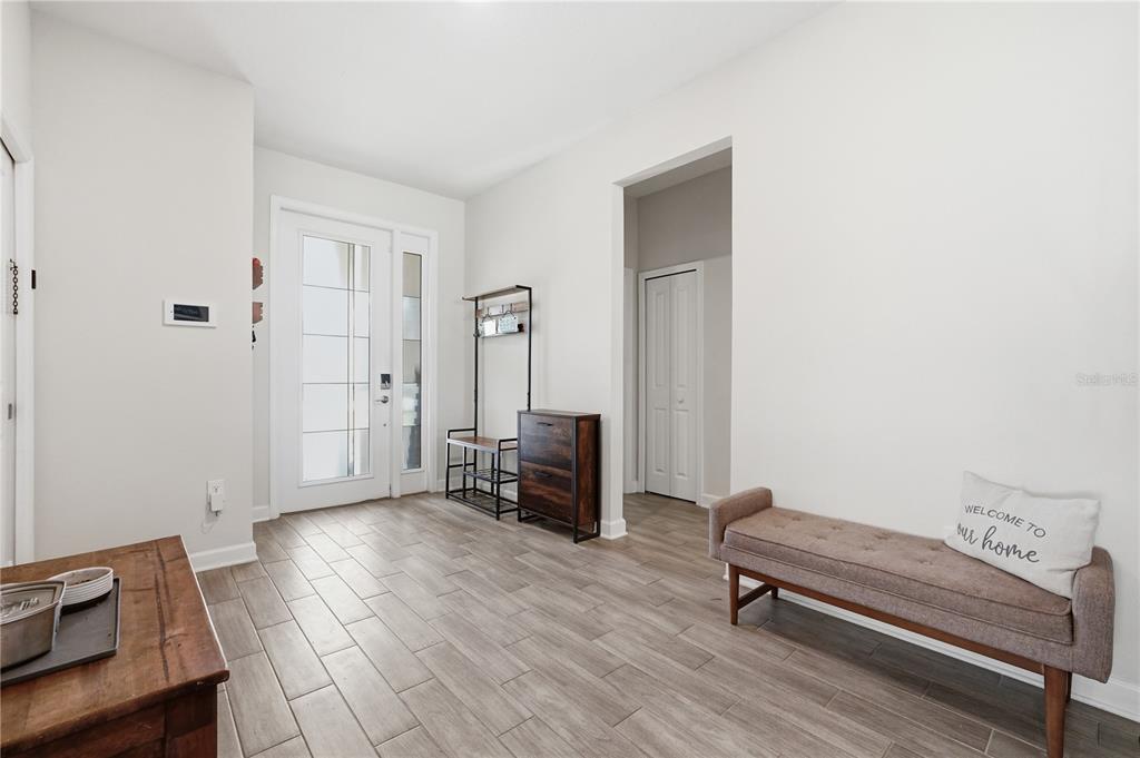 A bright entryway features wood-look tile flooring, a white front door, and a wooden bench — 8954 FLUFFY LIE COURT, DAVENPORT, FL