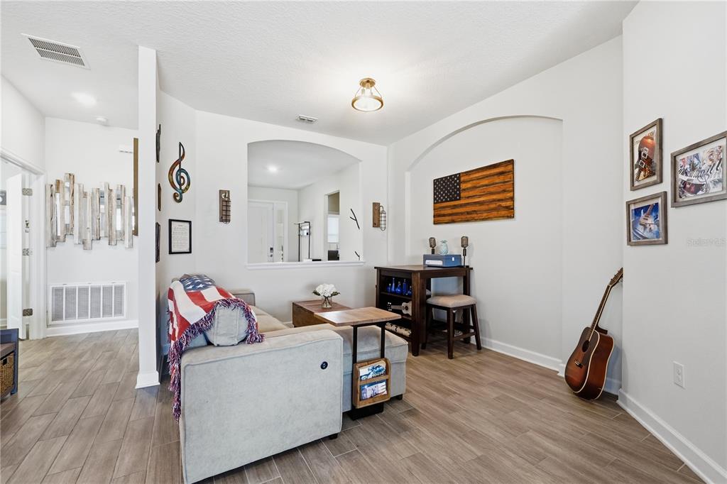 A living area features wood-look tile flooring, a gray sofa, and a wooden American flag — 8954 FLUFFY LIE COURT, DAVENPORT, FL