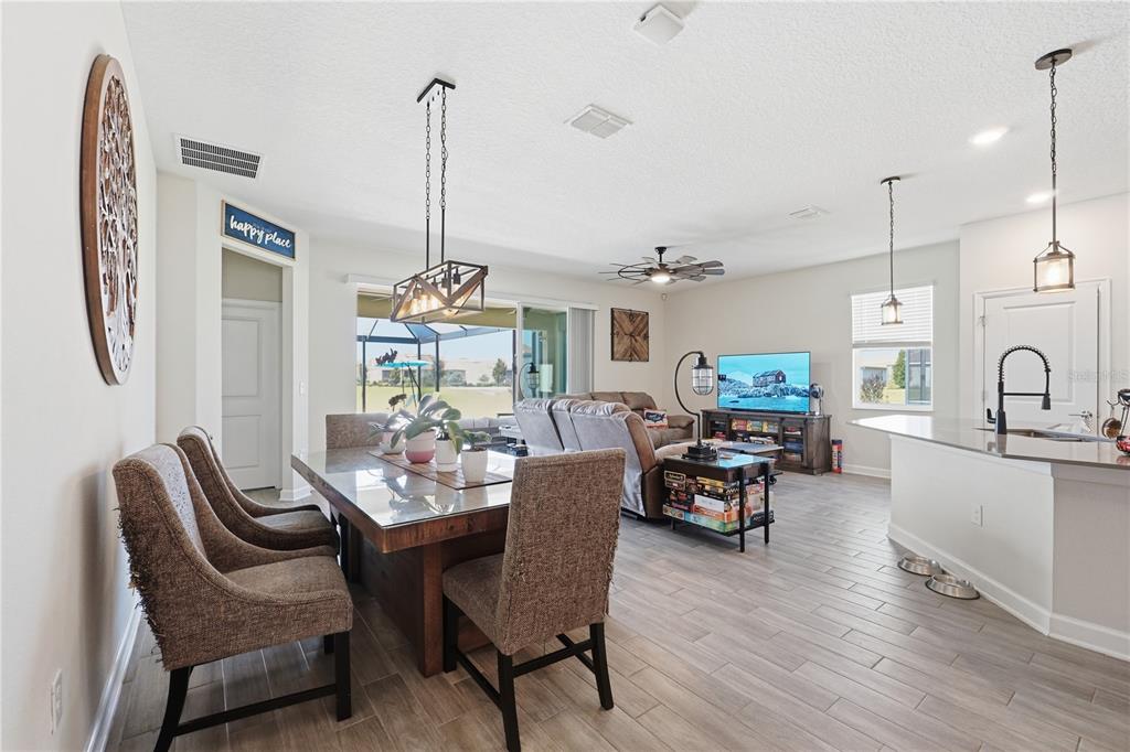 An open-concept living and dining area features tile flooring, a kitchen island, and sliding glass doors — 8954 FLUFFY LIE COURT, DAVENPORT, FL