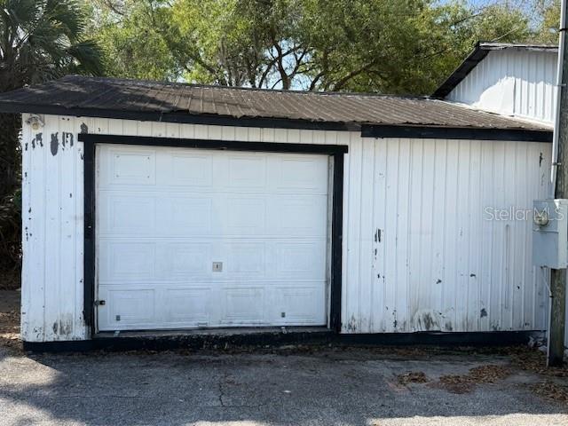 A detached white garage with a dark metal roof and a single sectional door — 323 N DELAWARE AVENUE UNIT 9, DELAND, FL