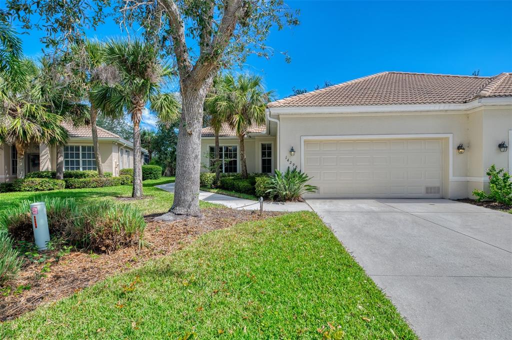 A single-story house with a beige stucco exterior, a two-car garage, and surrounding palm trees — 14298 RESERVE COURT, PORT CHARLOTTE, FL