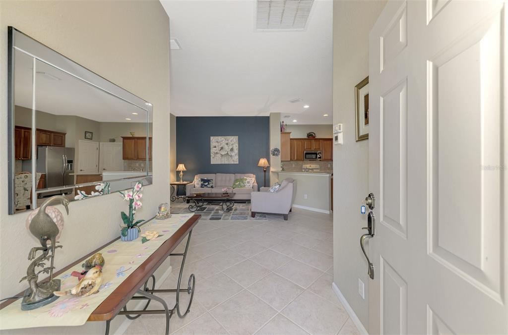 An entryway leads into an open-concept living room with tile floors and a dark accent wall — 14298 RESERVE COURT, PORT CHARLOTTE, FL