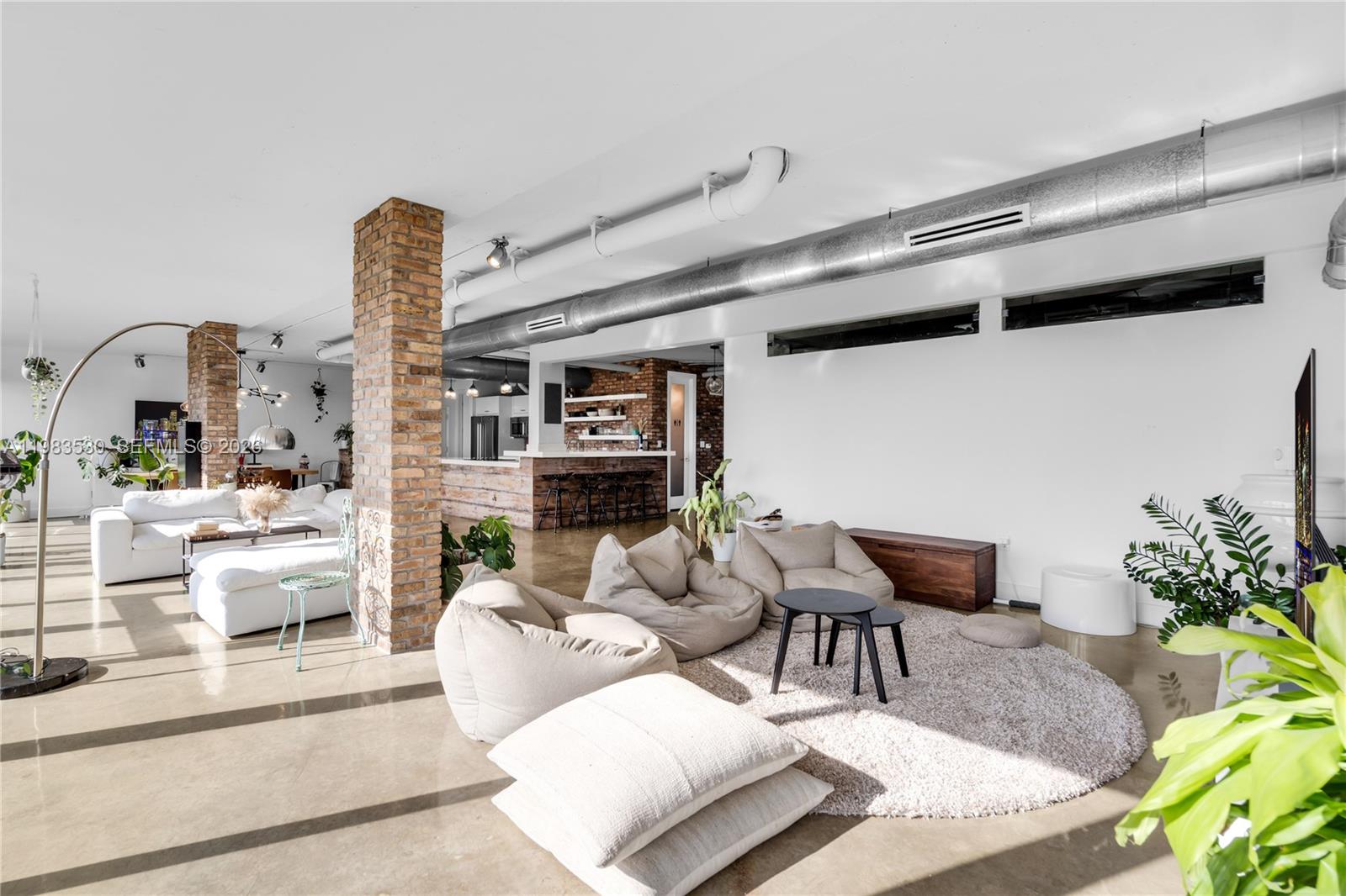 A spacious open-concept living area features polished concrete floors, exposed brick columns, and industrial ductwork — 5701 Biscayne Blvd # 9, Miami FL 33137, MIAMI, FL