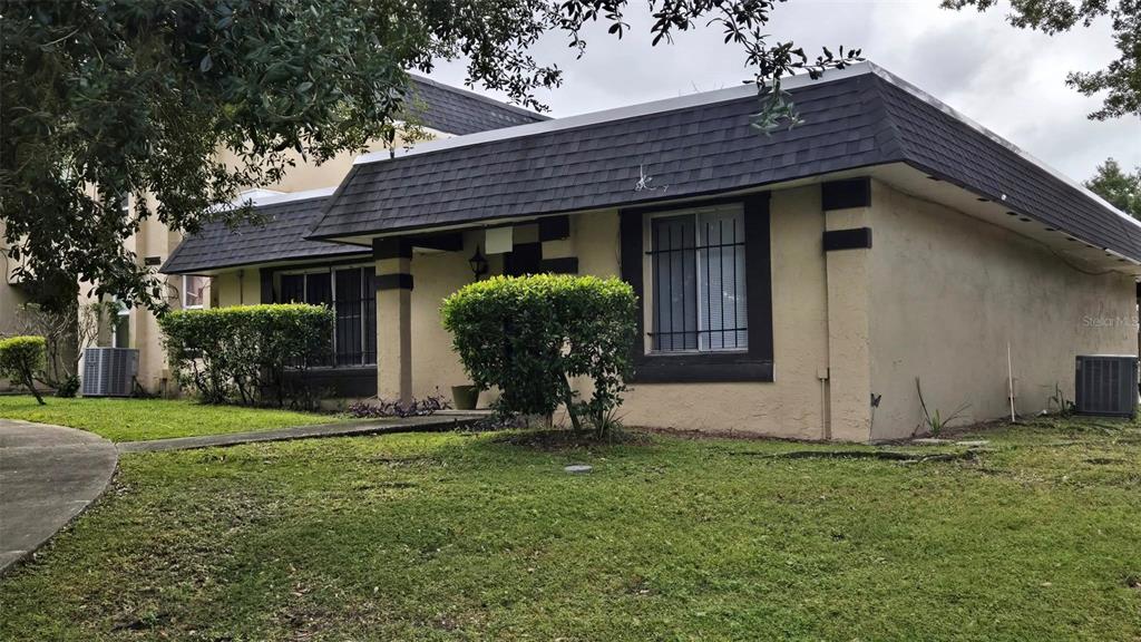 A single-story house with a dark mansard roof, tan stucco walls, and window security bars — 5433 BROOKSWOOD WAY UNIT 806, ORLANDO, FL