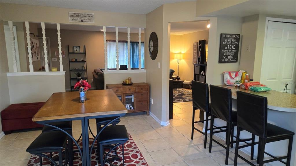 A dining area with a wooden table and stools sits adjacent to a kitchen counter — 5433 BROOKSWOOD WAY UNIT 806, ORLANDO, FL