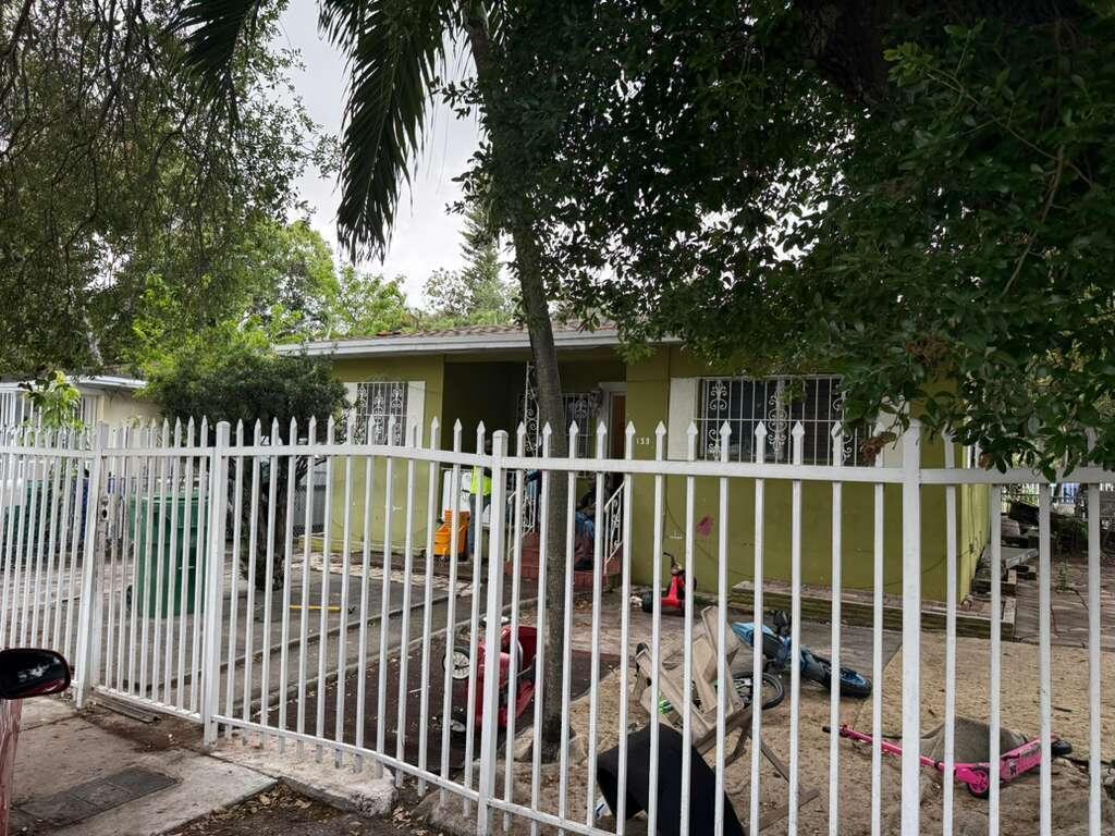 A single-story lime green house with a white metal fence and a front yard — 139 NE 63rd Street, Miami FL 33138, MIAMI, FL