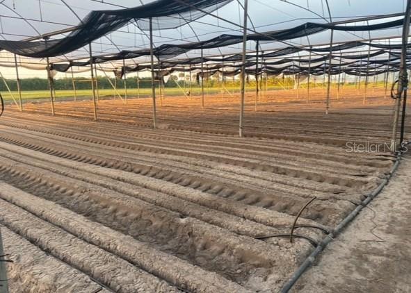 An outdoor agricultural field features rows of tilled soil under a large shade cloth structure — 6150 PRINGLE LANE, IMMOKALEE, FL