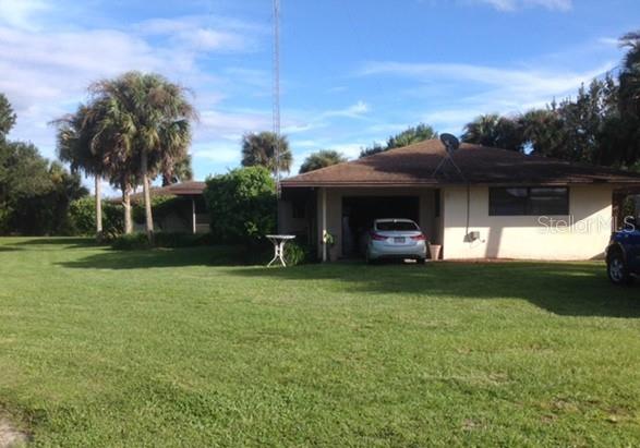 A single-story house with a garage and a large front lawn under a blue sky — 6150 PRINGLE LANE, IMMOKALEE, FL