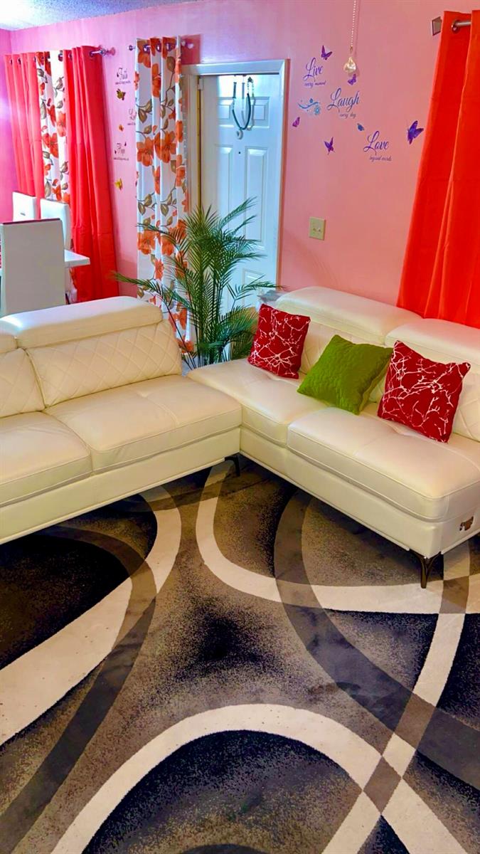 A living room features white leather sofas, a patterned rug, and pink walls — 2004 Maplewood Drive # 2004, FL 33415, FL