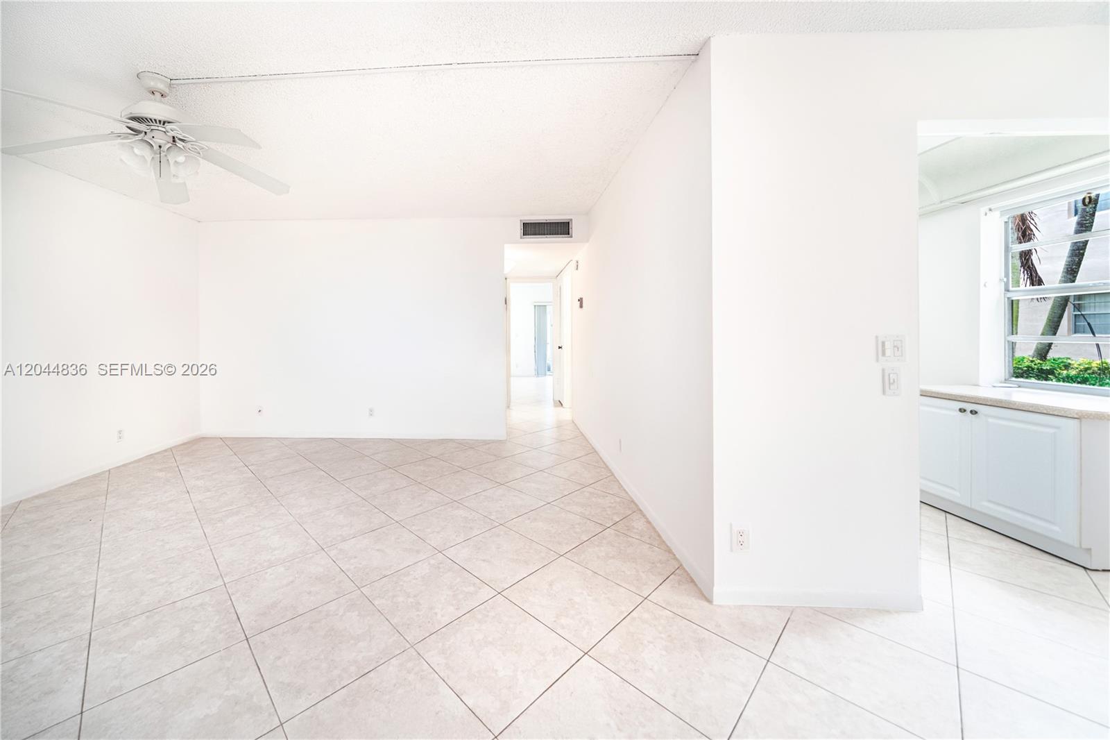 A bright, empty room features white walls, light-colored tile flooring, and a ceiling fan — 642 N Normandy  N # 642, Delray Beach FL 33484, DELRAY BEACH, FL