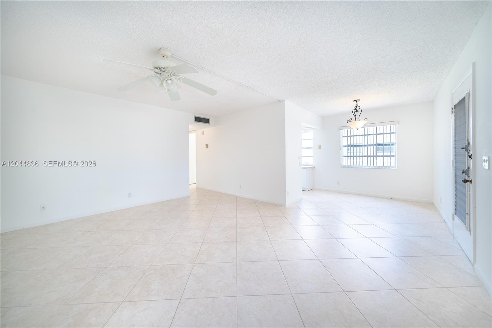 An open-concept living and dining area features white walls, tile flooring, and a ceiling fan — 642 N Normandy  N # 642, Delray Beach FL 33484, DELRAY BEACH, FL