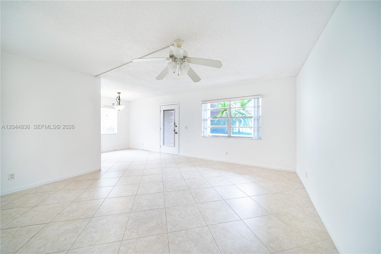 A bright, empty living room features white walls, light-colored tile flooring, and a ceiling fan — 642 N Normandy  N # 642, Delray Beach FL 33484, DELRAY BEACH, FL