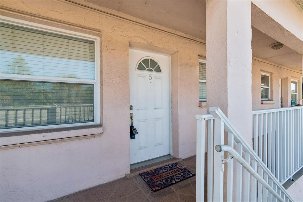 A white front door labeled with the number five sits on a pink exterior walkway — 525 73RD AVE UNIT 5, ST PETE BEACH, FL