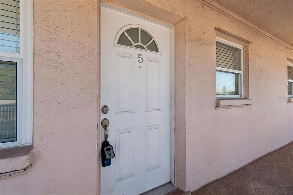 A white front door labeled with the number five on a light pink stucco exterior — 525 73RD AVE UNIT 5, ST PETE BEACH, FL
