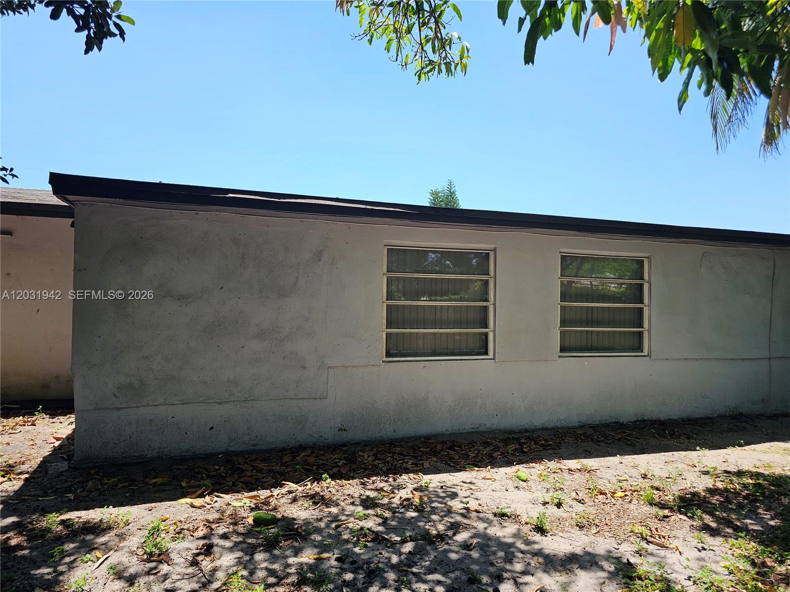 The exterior of a white stucco building features two jalousie windows under a dark roof — 4431 NW 23rd Ct, Lauderhill FL 33313, LAUDERHILL, FL