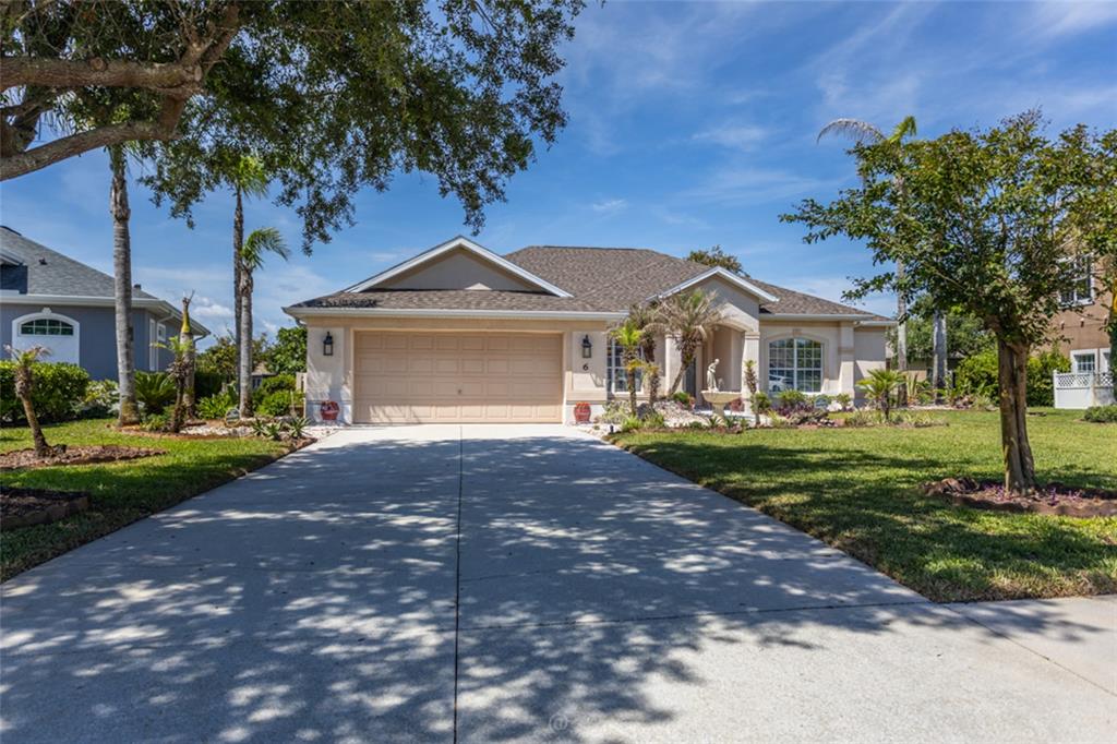 A single-story suburban house with a tan stucco exterior, a two-car garage, and palm trees — 6 S LAKEWALK DRIVE, PALM COAST, FL