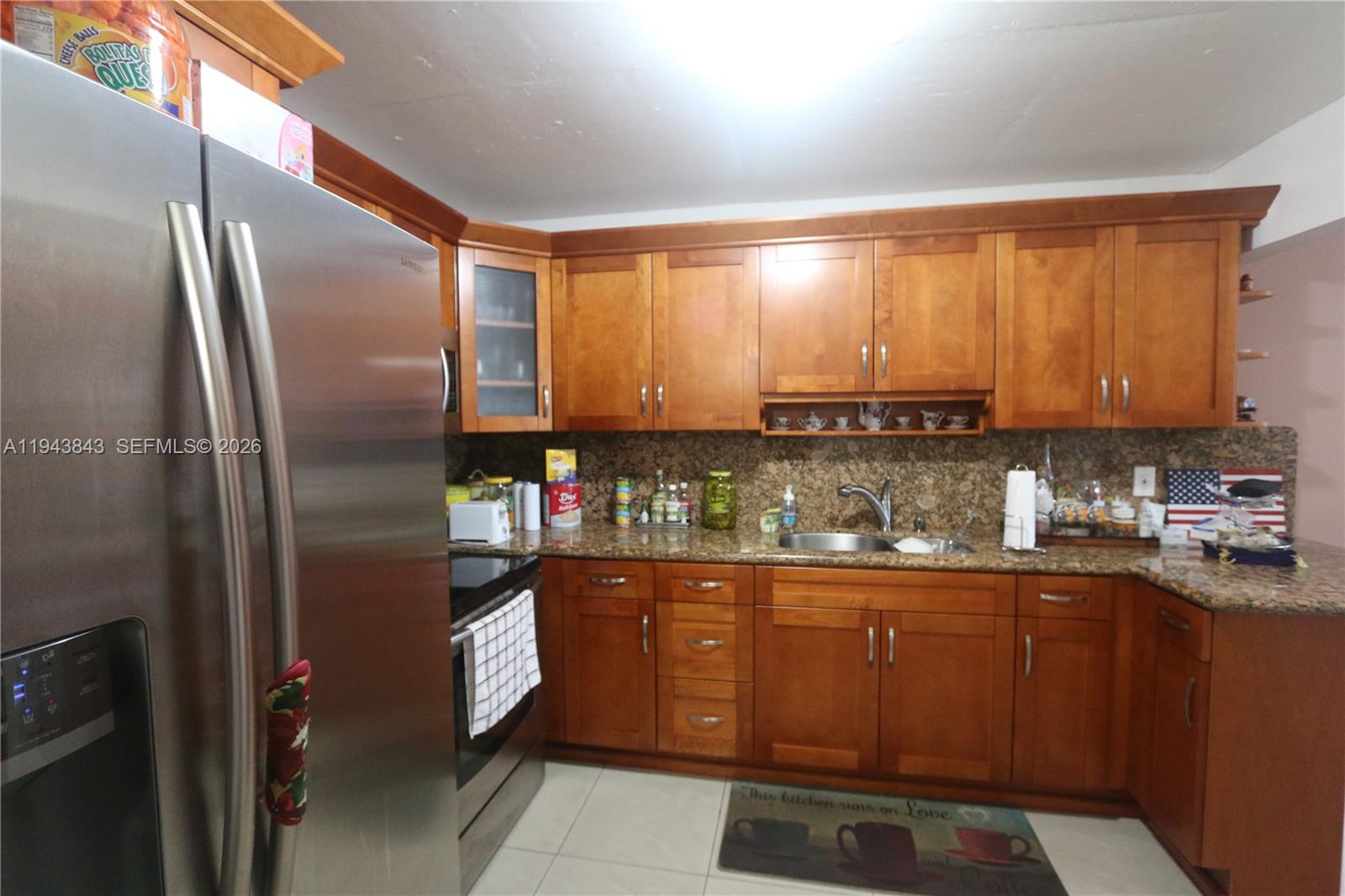 A kitchen features wood cabinets, granite countertops, stainless steel appliances, and a tiled floor — 6940 NW Miami Gardens Dr # 430, Hialeah FL 33015, HIALEAH, FL