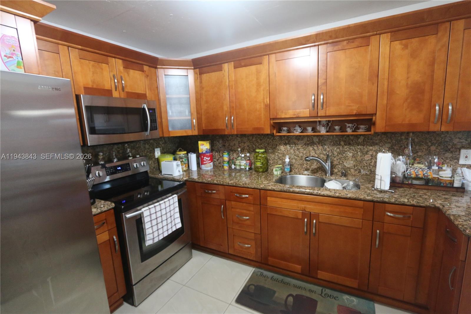 A kitchen features wood cabinets, granite countertops, and stainless steel appliances — 6940 NW Miami Gardens Dr # 430, Hialeah FL 33015, HIALEAH, FL