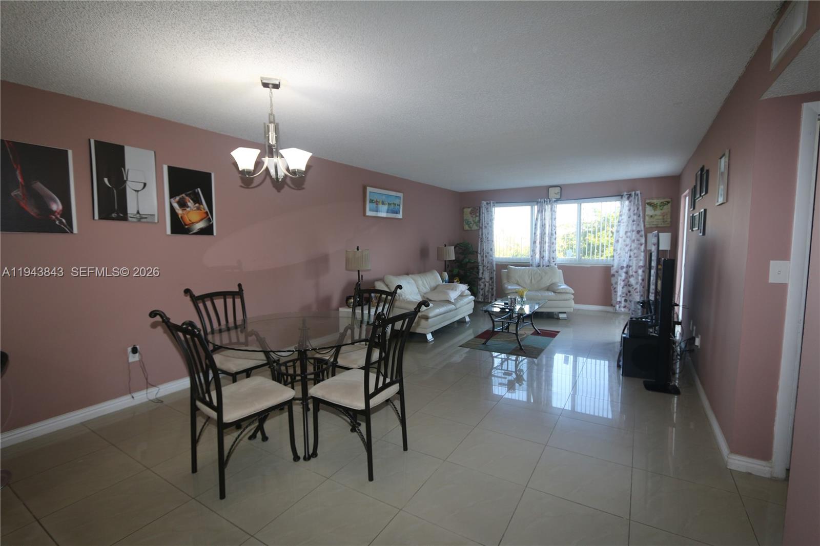 A living and dining area features light tile floors, pink walls, and white furniture — 6940 NW Miami Gardens Dr # 430, Hialeah FL 33015, HIALEAH, FL