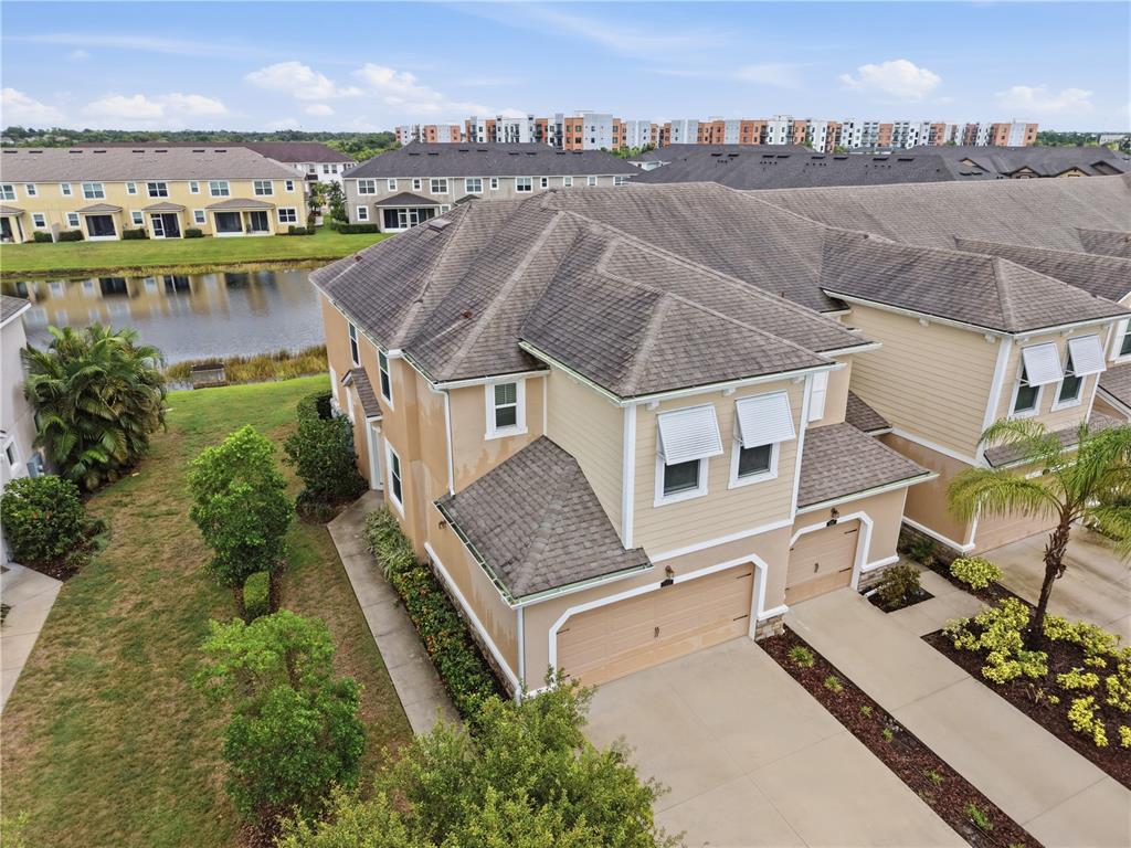 An aerial view shows a two-story tan townhouse with a shingled roof and garages — 5553 PLEASANTVIEW COURT, BRADENTON, FL