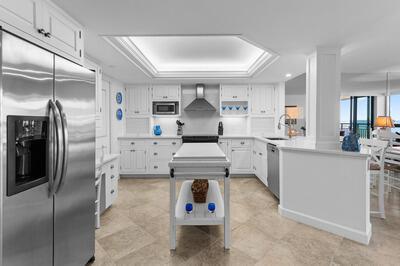 A white kitchen features stainless steel appliances, a central island, and light-colored tile flooring — FORT PIERCE, FL