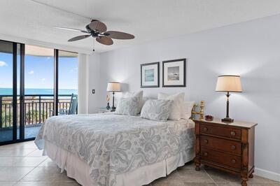 A bedroom features a king bed, a wooden nightstand, and a balcony overlooking the ocean — FORT PIERCE, FL