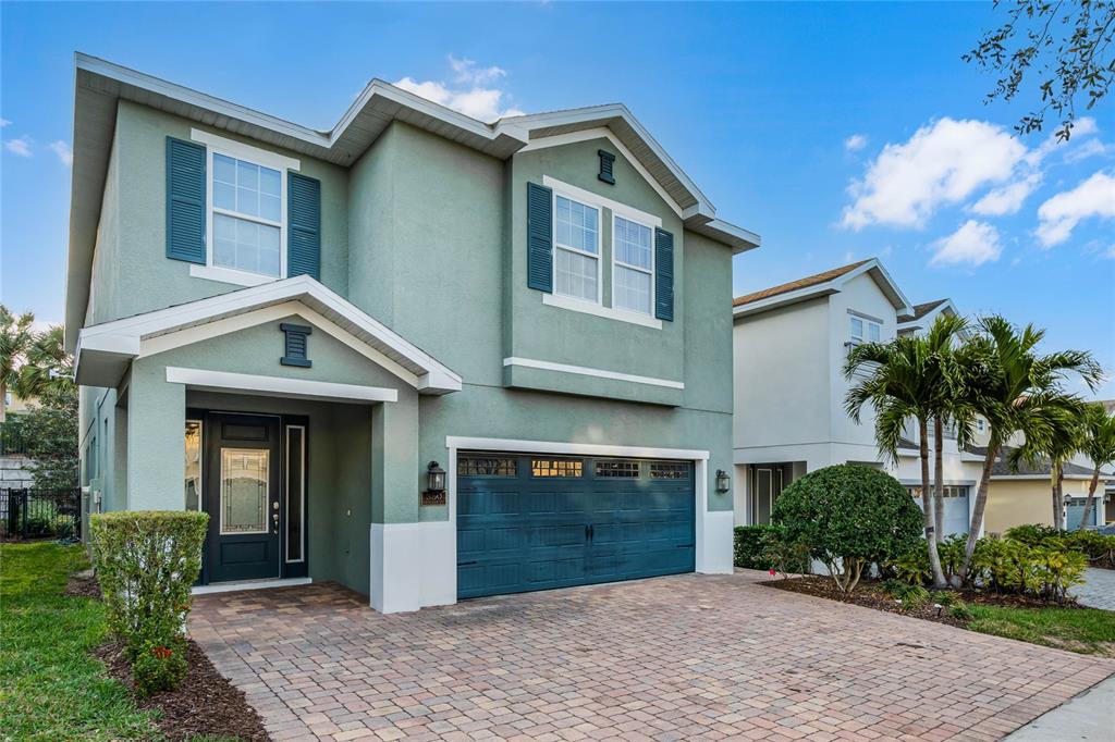 A two-story house with a light green stucco exterior, dark blue shutters, and a paved driveway — 350 PENDANT COURT, KISSIMMEE, FL