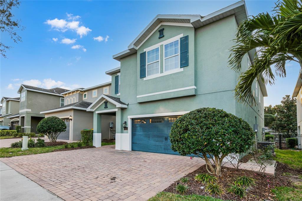 A two-story house with a teal garage door, light green stucco siding, and paved driveway — 350 PENDANT COURT, KISSIMMEE, FL