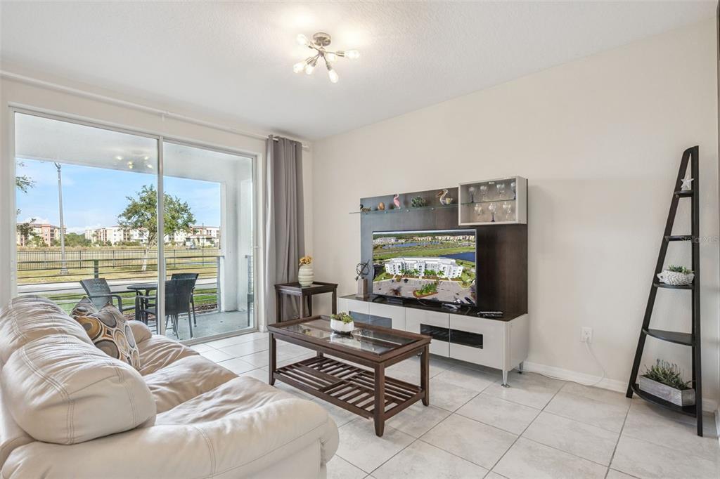 A living room features tile floors, a white sofa, a media console, and a sliding door — 4721 CLOCK TOWER DRIVE UNIT 107, KISSIMMEE, FL