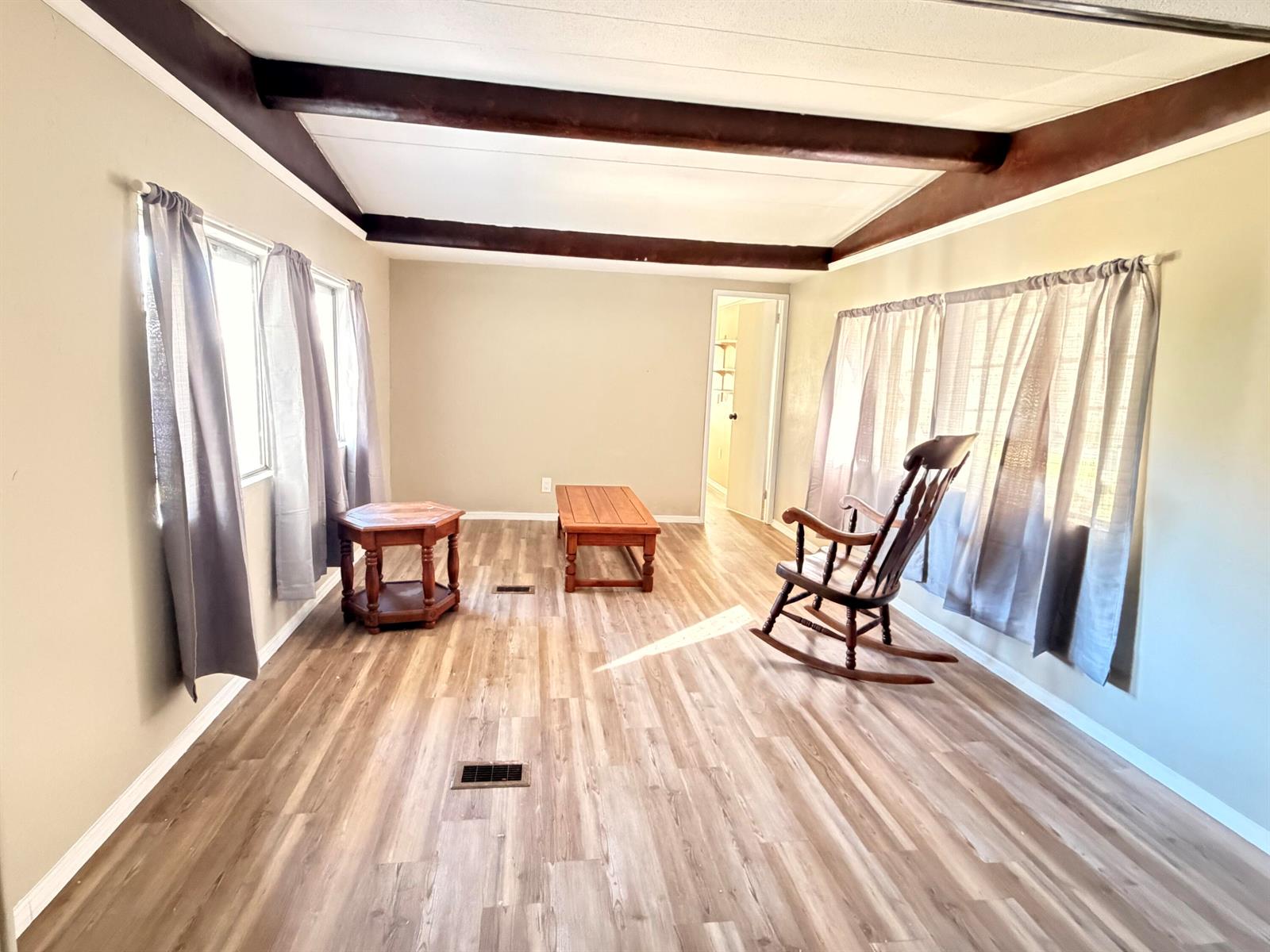A living room features wood-look flooring, exposed ceiling beams, and a wooden rocking chair — 2313 SE 30th Street, Okeechobee FL 34974, OKEECHOBEE, FL