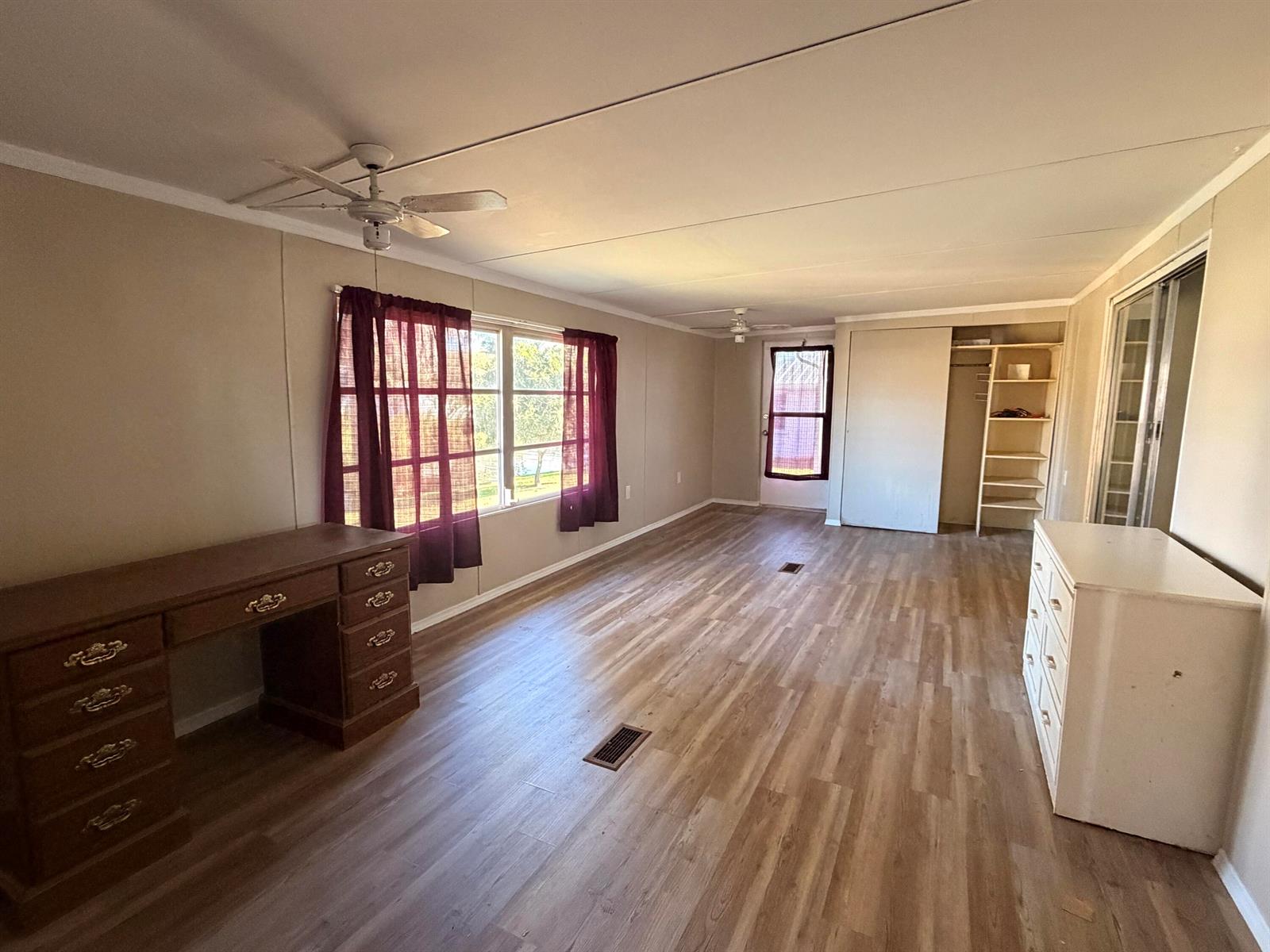 A spacious room features light wood-look flooring, a wooden desk, a white dresser, and windows — 2313 SE 30th Street, Okeechobee FL 34974, OKEECHOBEE, FL