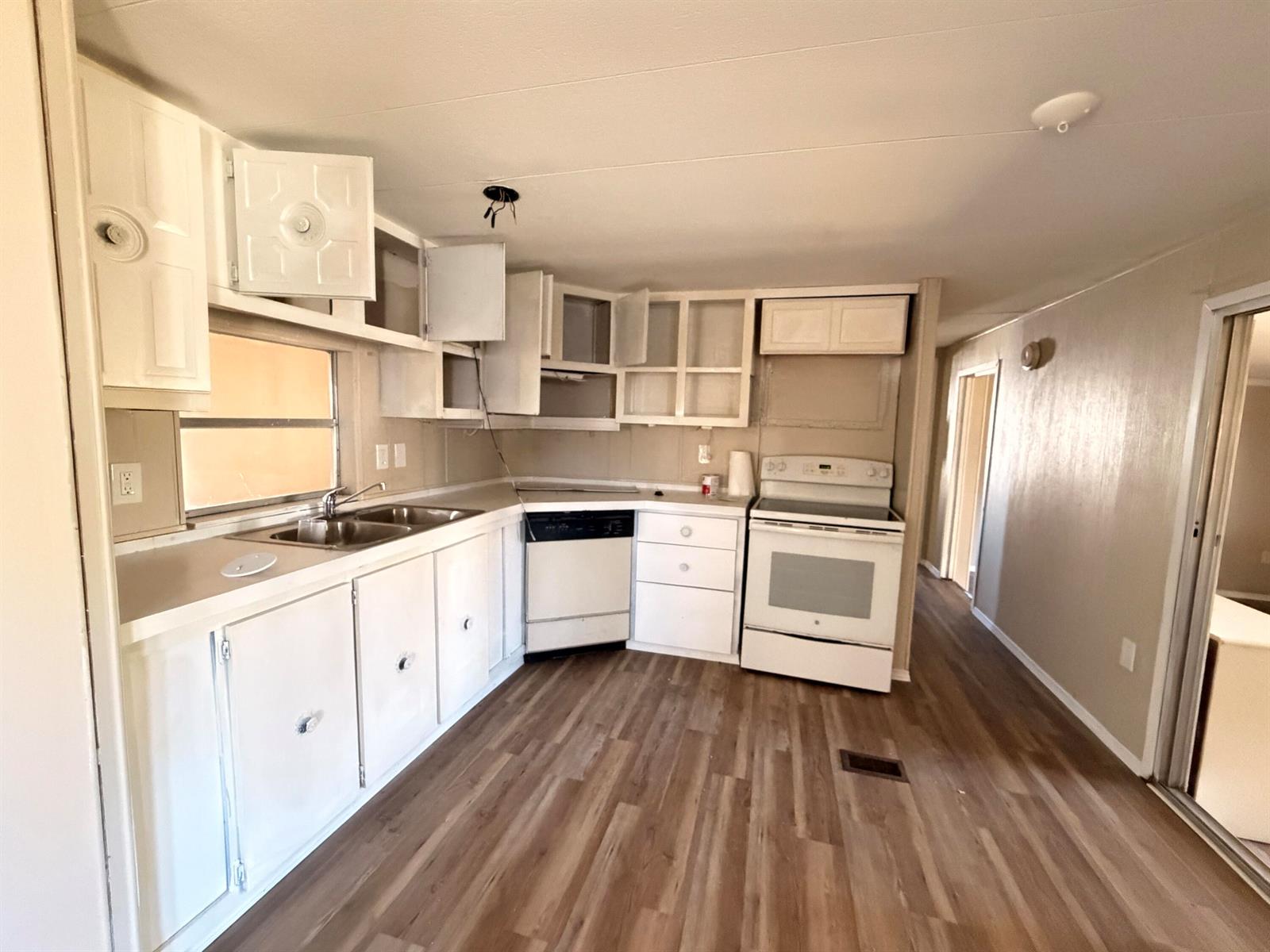 A kitchen features white cabinets, a double sink, a dishwasher, and a white electric stove — 2313 SE 30th Street, Okeechobee FL 34974, OKEECHOBEE, FL
