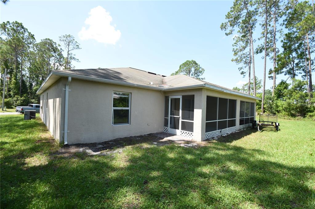 The exterior of a beige house features a screened-in porch and a grassy backyard — 30 ETON LANE, PALM COAST, FL