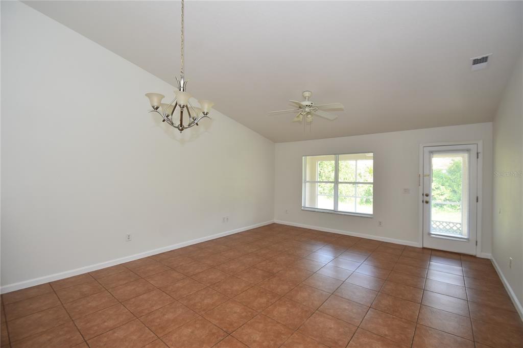 An empty room with vaulted ceilings, a chandelier, a ceiling fan, and tiled flooring — 30 ETON LANE, PALM COAST, FL