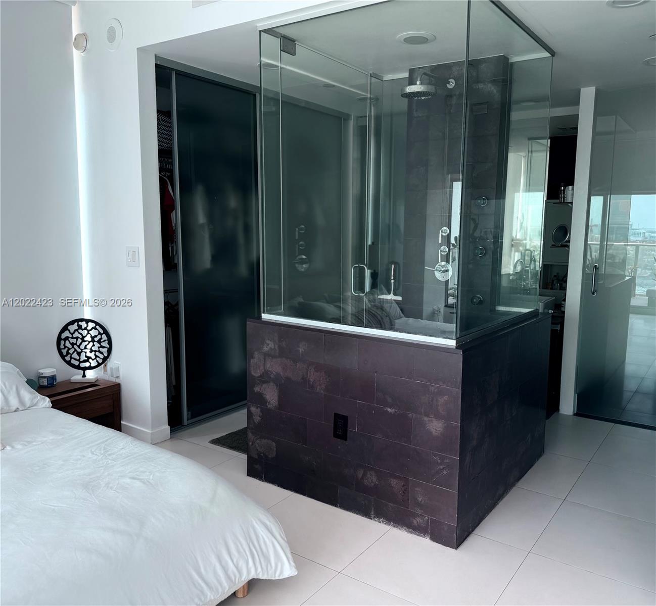 A bedroom features a glass-enclosed shower with dark stone tile base and white flooring — 1040 Biscayne Blvd # 1606, Miami FL 33132, MIAMI, FL