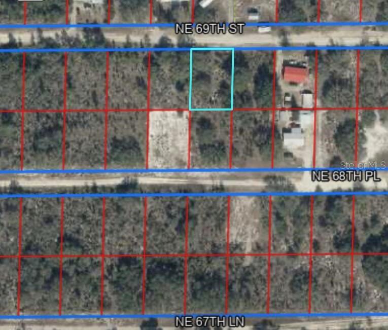 This aerial map shows a vacant rectangular lot outlined in blue between two dirt roads — NE 69TH STREET, WILLISTON, FL