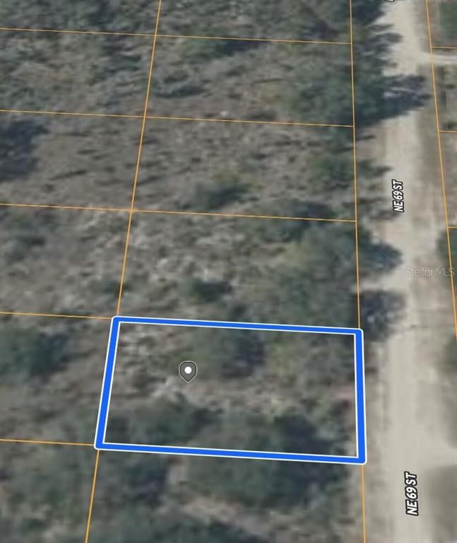 This is an aerial map view showing a vacant, rectangular lot outlined in blue — NE 69TH STREET, WILLISTON, FL