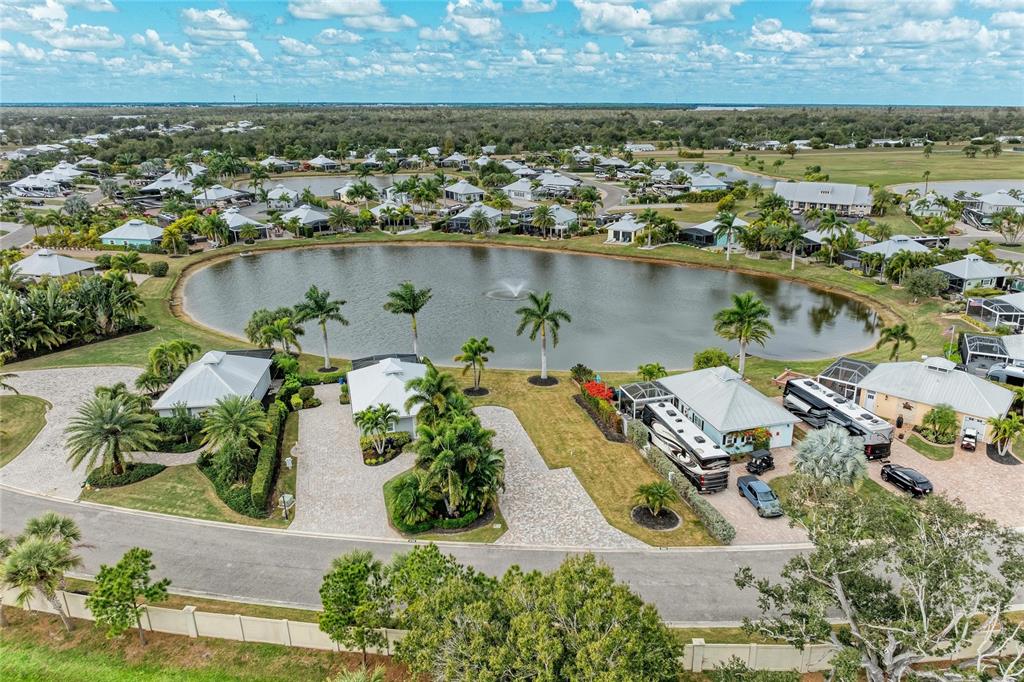 An aerial view shows a residential community with houses, RVs, and a central pond — 8801 SW SAND CRANE CIRCLE LOT 39, ARCADIA, FL