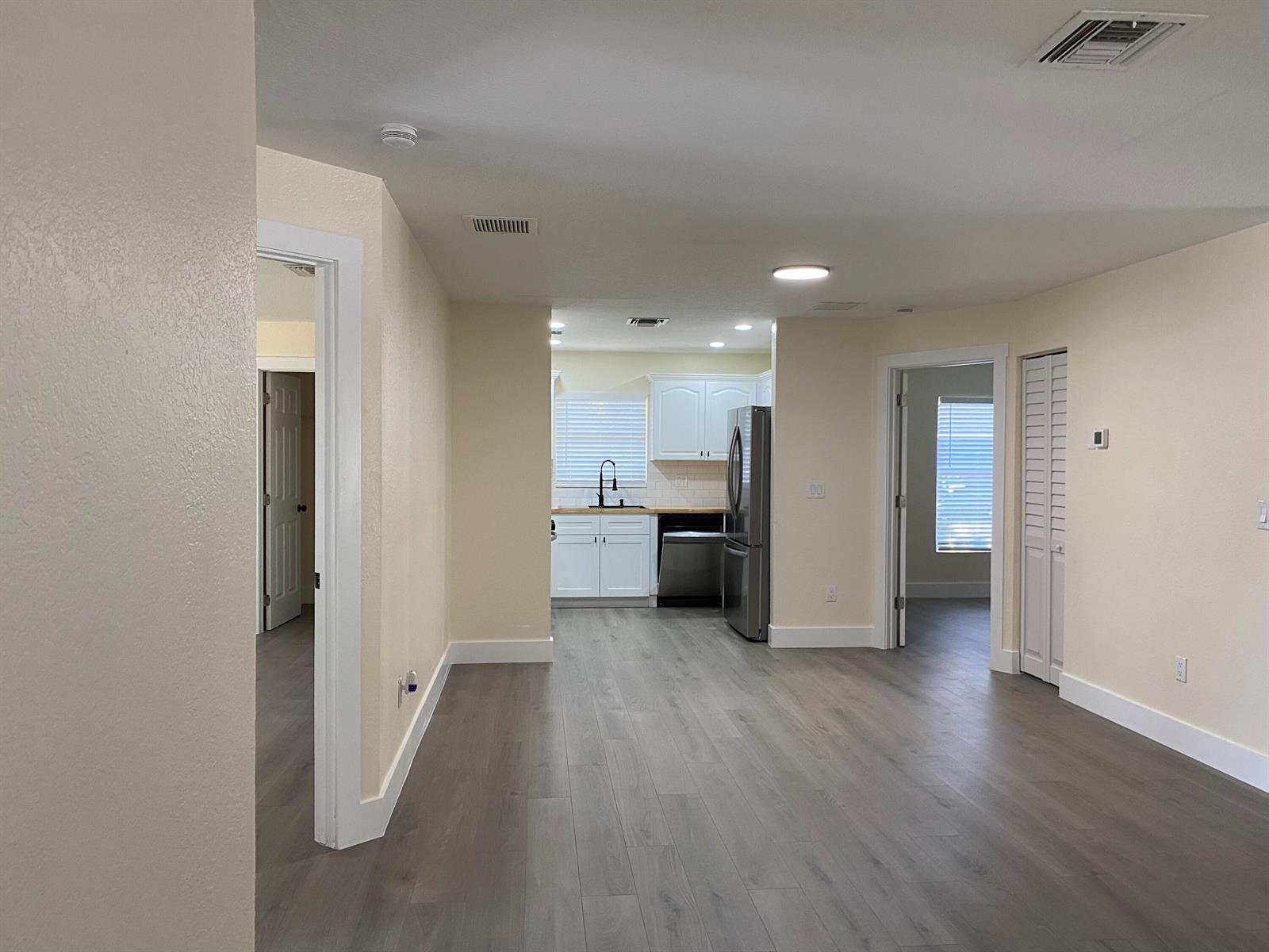 An open-concept living area features light-colored walls, gray wood-look flooring, and a white kitchen — 176 SW 5th Court, Deerfield Beach FL 33441, DEERFIELD BEACH, FL