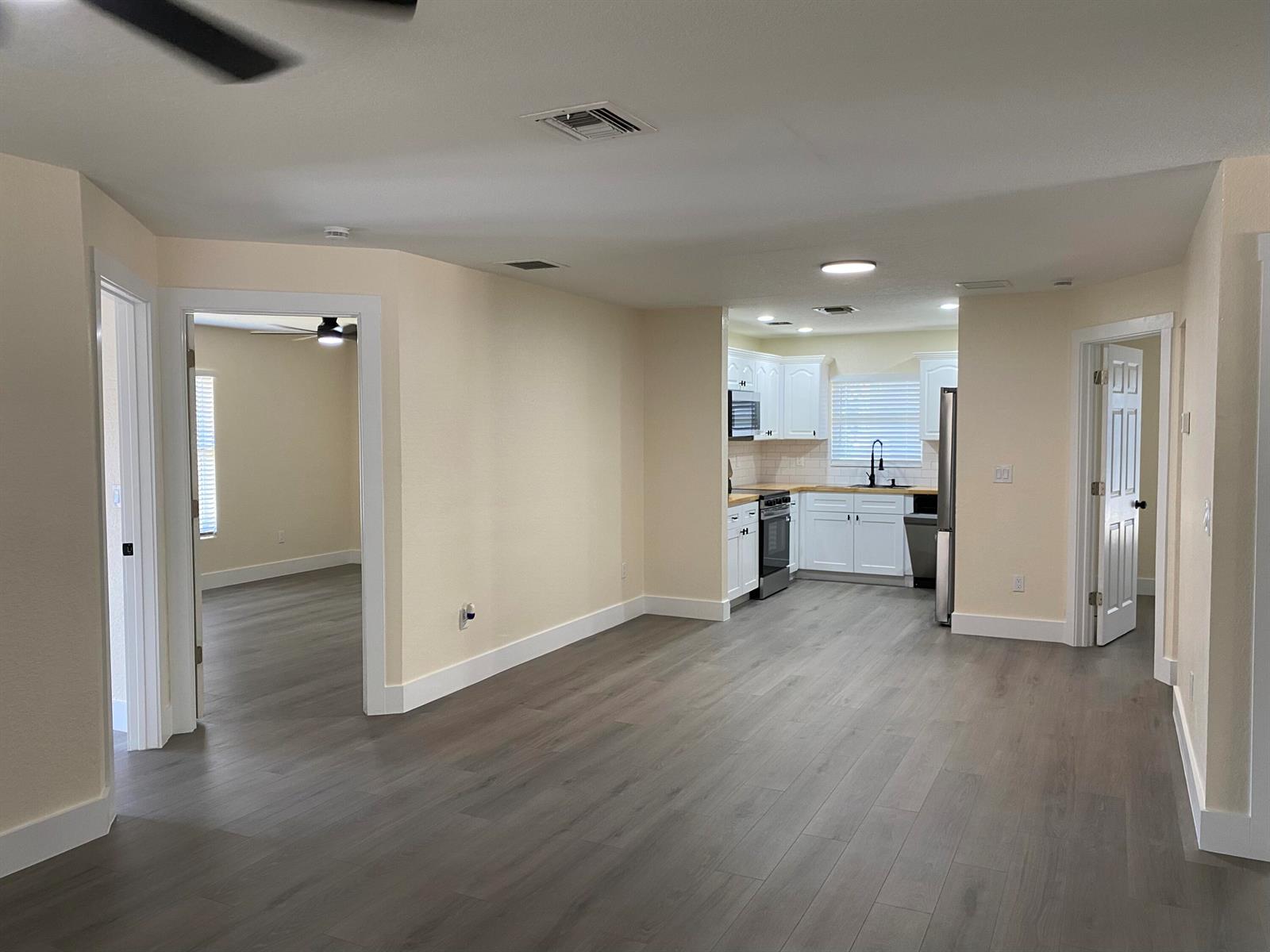An open-concept living area features light-colored walls, gray wood-look flooring, and a white kitchen — 176 SW 5th Court, Deerfield Beach FL 33441, DEERFIELD BEACH, FL