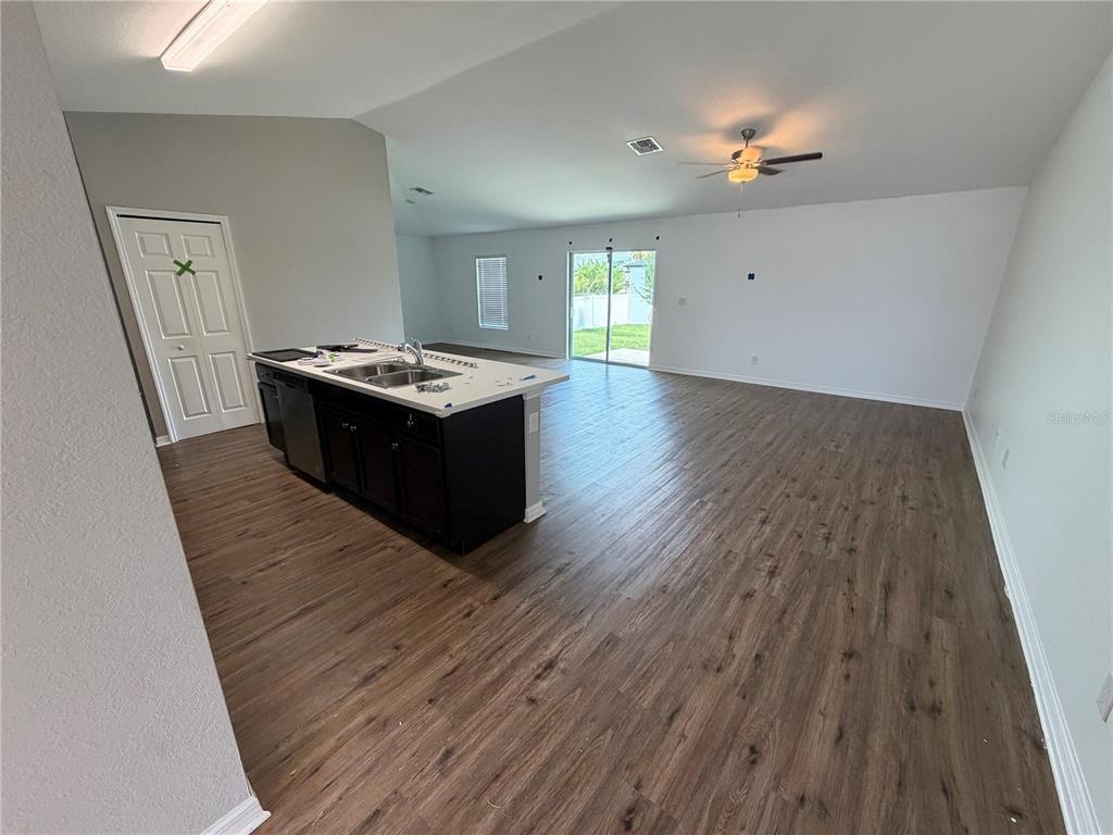 An open-concept living area features a kitchen island with dark cabinets and wood-look flooring — 2828 SW 2ND TERRACE, CAPE CORAL, FL