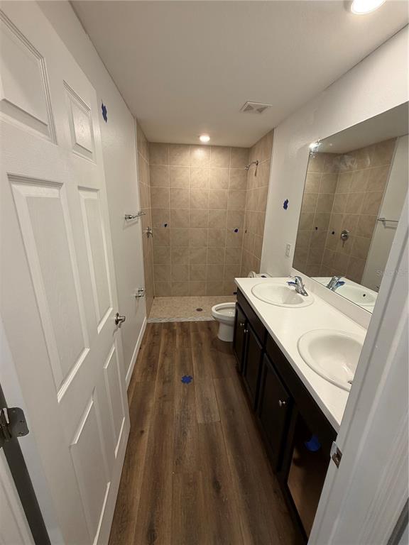 A bathroom features a double vanity, a walk-in tiled shower, and wood-look flooring — 2828 SW 2ND TERRACE, CAPE CORAL, FL
